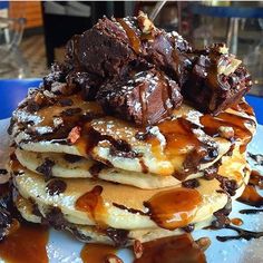 a stack of pancakes covered in chocolate and caramel drizzled with syrup