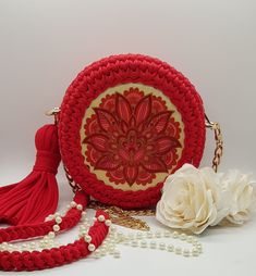 a red purse sitting on top of a table next to a white flower and chain