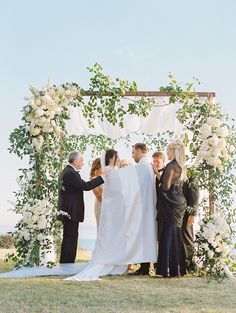 a group of people standing next to each other under a wedding arch