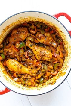 a pot filled with chicken and vegetables on top of a white table