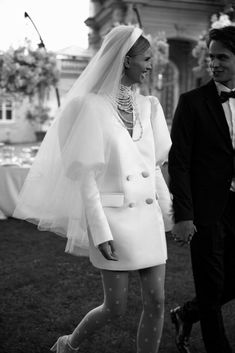 a man and woman dressed in wedding attire walking down the street with an advertisement on it