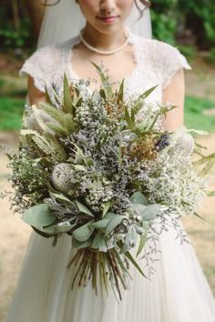 a woman in a wedding dress holding a bridal bouquet and looking at the camera