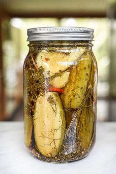 pickles and herbs in a glass jar on a table