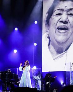 a woman singing on stage in front of a large photo