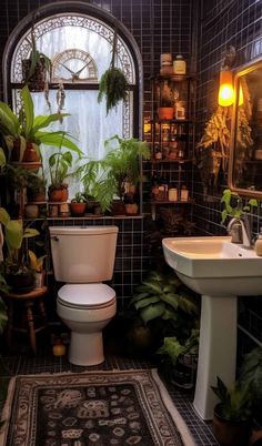 a bathroom with a toilet, sink and plants in the window sill on the wall