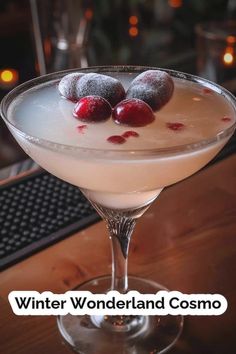 a drink in a martini glass with two cherries on the rim and text that reads winter wonderland cosmo