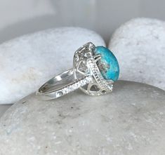 "An OOAK cabochon oval-shaped natural 6.07ct Turquoise Ring adorned with a halo of petite white topaz complimented with heart cut outs around the basket, handcrafted in sterling silver is a striking engagement/promise/statement ring. Wrapped in a box ready for gift-giving. This ring is a FINAL SALE. (r.egt.85) View our vast collection of Turquoise Rings: We can also make your custom dream ring https://www.etsy.com/shop/Belesas?ref=seller-platform-mcnav&search_query=turquoise+ring Ring Info - Anniversary Oval Cabochon Turquoise Ring In Fine Jewelry Style, Elegant Oval Turquoise Ring With Accent Stones, Oval Turquoise Ring With Accent Stones, Fine Jewelry Sterling Silver Oval Turquoise Ring, Elegant Oval Turquoise Ring With Large Stone, Round Turquoise Ring Perfect As A Gift, Turquoise Oval Rings With Natural Stones, Oval Cabochon Turquoise Ring For Anniversary, Oval Turquoise Ring With Bezel Setting For Anniversary