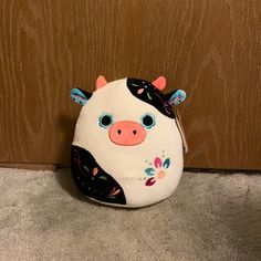 a stuffed cow sitting on the floor next to a door