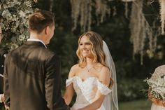 a bride and groom are smiling at each other as they stand in front of the altar