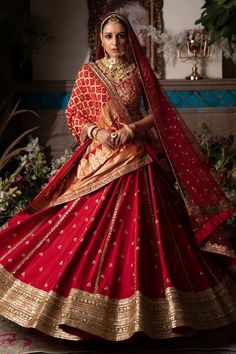 a woman in a red and gold bridal gown, with her hands on her hips