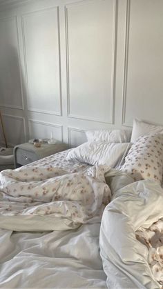 an unmade bed with white sheets and pillows