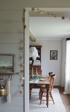 the dining room table is set for two with gold stars hanging from the wall above it