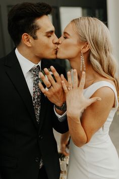 a man and woman kissing each other in front of a building