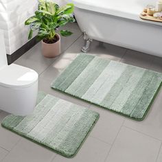 two bathroom rugs sitting on the floor in front of a bathtub and toilet