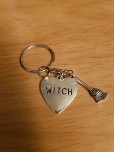 a heart shaped keychain with the word witch written on it and an arrow charm