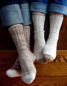 two people wearing socks and sitting on a wooden floor