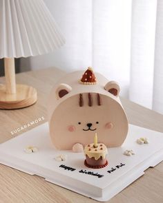 a small bear holding a birthday cake with a candle in it