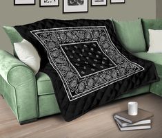 a couch with a blanket on top of it next to some pictures and a cup