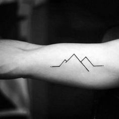 a person's arm with a line drawing on it and mountains in the background