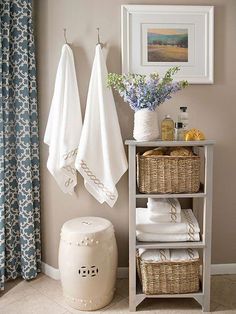 a bathroom with two towels hanging on the wall next to a shelf filled with folded towels