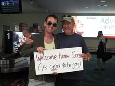 two men standing next to each other holding a sign