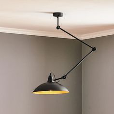 a black lamp hanging from the ceiling in a room with gray walls and flooring