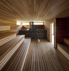 the inside of a sauna with wooden flooring and brick fireplace in the center