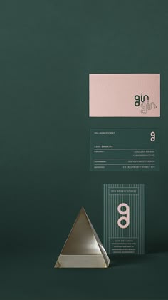 the business card is placed next to an unusual metal object on a green background with white and pink accents