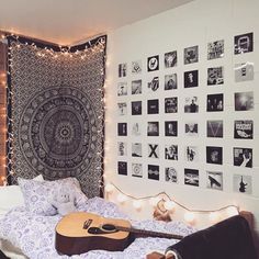 a bed room with a guitar on the floor and a tapestry hanging over the headboard