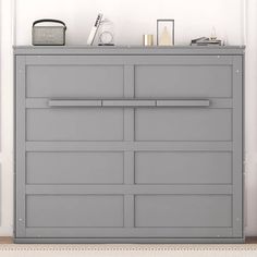 a gray dresser sitting in front of a white wall