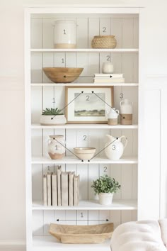 a white book shelf filled with books and vases