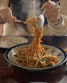 a person eating noodles with an egg on top