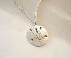 "Sand Dollar Necklace Silver Sand Dollar Pendant Beach Jewelry Bridesmaid Necklace Sand dollar Necklace Ever stroll the beach and come upon a sand dollar, well it would be you're lucky day, they are real living creatures and are so beautiful. Sand dollar measures approx. 24 mm x 23mm or 1\" in diameter. A silver matte silver dollars hangs from silver chain. The silver dollar is so realistic looking, it is a matte silver and is slightly domed like a real sand dollar. You can feel the detail in th Sand Dollar Necklace, Sand Dollar Pendant, Jewelry Bridesmaid, Lucky Day, Sand Dollar, Bridesmaid Necklace, Silver Dollar, Beach Jewelry, Necklace Silver