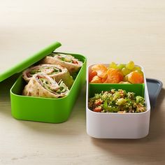 two green containers filled with food on top of a wooden table