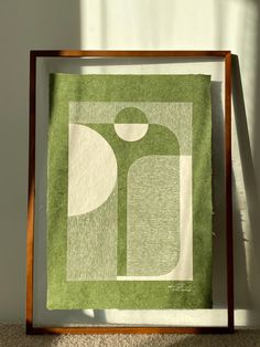 a green and white quilt hanging on a wall next to a wooden framed artwork piece