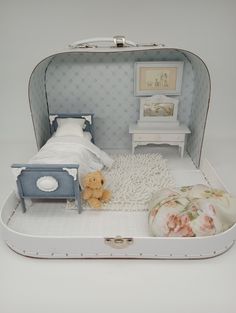 an open suitcase with a bed and a teddy bear in the room next to it