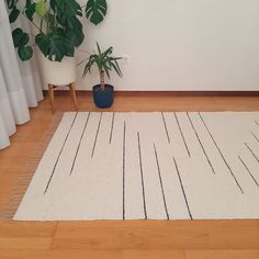 a white rug sitting on top of a wooden floor next to a potted plant