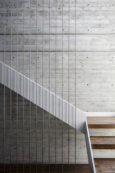 a white stair case next to a wooden floor and wall with metal bars on it