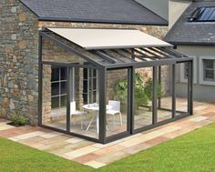 a house with a glass roof and an awning on the side of it in front of a stone wall