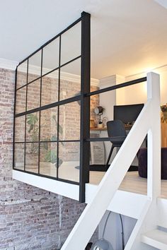 there is a white stair case in the living room with brick walls and flooring