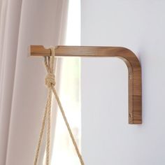 a wooden shelf hanging from the side of a wall with rope attached to it's sides