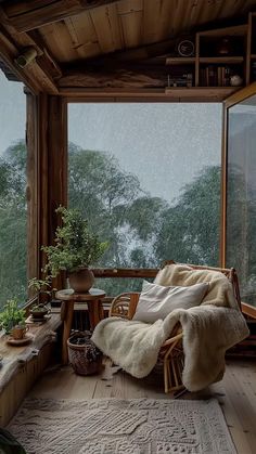 a wooden porch with a chair and table in the middle of it on a rainy day