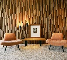 two chairs and a coffee table in front of a wall with wood panels on it