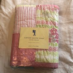 a pink and green patchwork quilt with a tag on the side that says surprise quilted sham