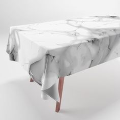 a marble table with wooden legs and a white cloth on the top that has an abstract design