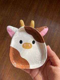 a hand holding a paper plate with a cow on it's face and horns