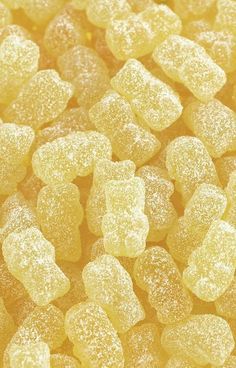 yellow gummy bears are piled together on top of each other with white sugar sprinkles