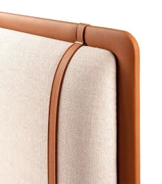 an upholstered headboard with a tan leather strip on it's side