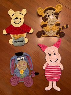 four crocheted winnie the pooh characters on a wooden floor