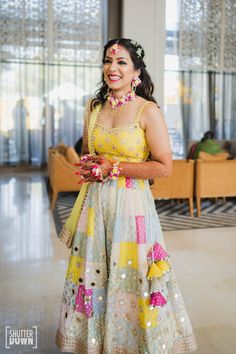 a woman in a yellow and white dress smiles at the camera while holding a bouquet